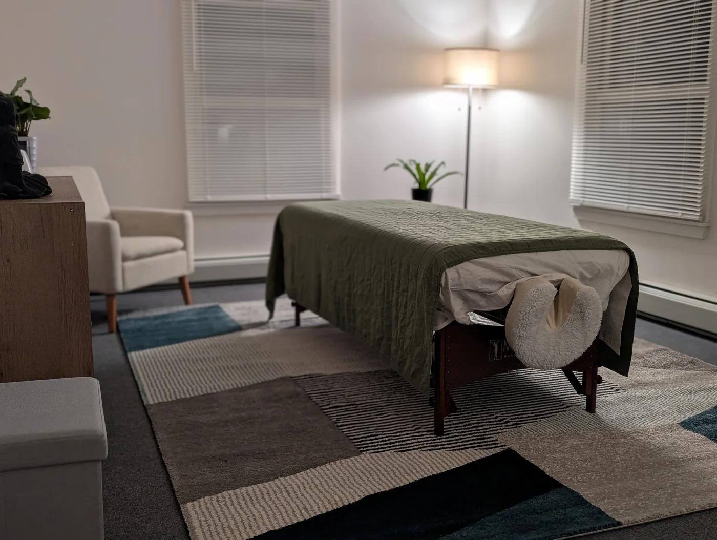 Calm massage room with treatment table and warm floor lamp