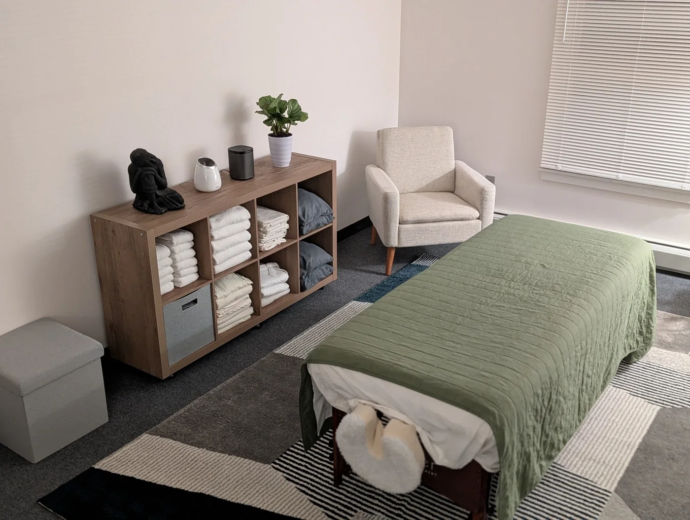 Sula Massage Therapy treatment room with sage massage table and linen storage